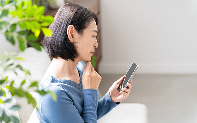 突然の血便に不安を感じてスマートフォンで調べている女性